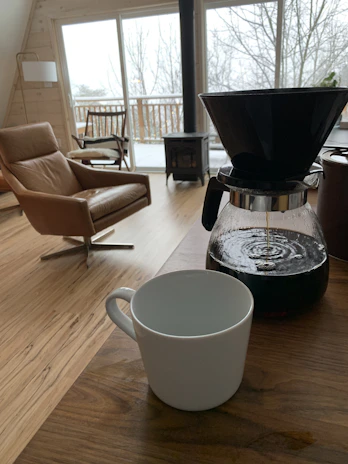 A cozy Alaskan home interior showcasing warm wooden flooring with snow-covered windows in the background.