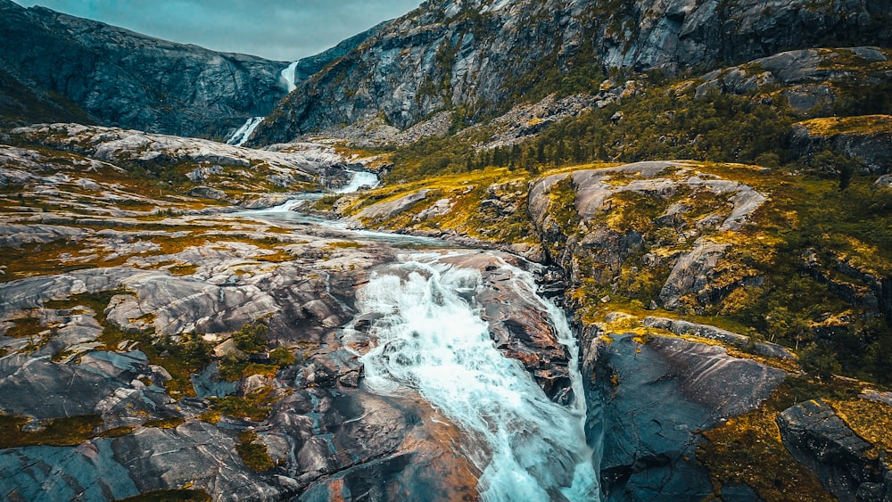 water falls on brown and green mountains