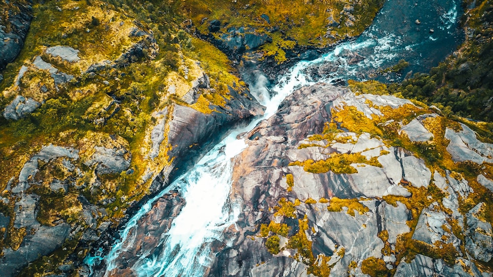 green and brown rock formation with water falls