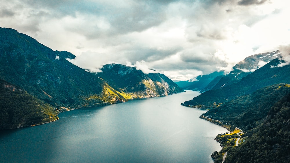 lago no meio das montanhas sob nuvens brancas