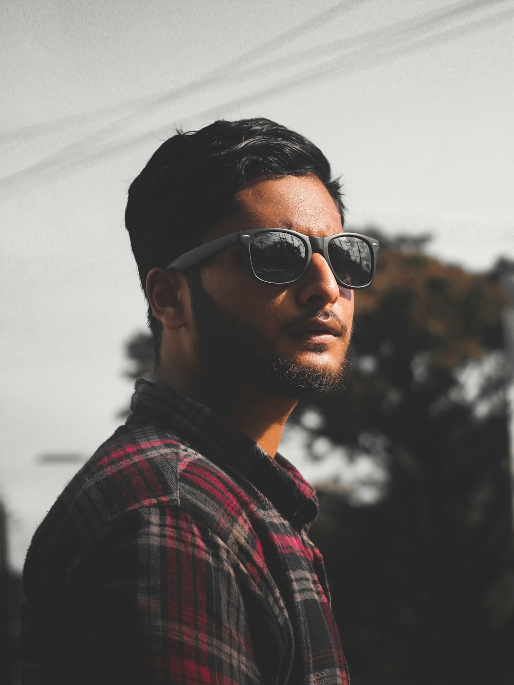 man in red white and black plaid shirt wearing black sunglasses