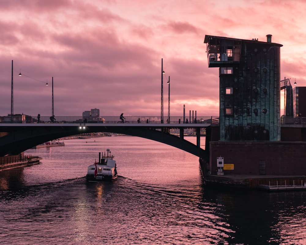 boat on water near bridge during sunset