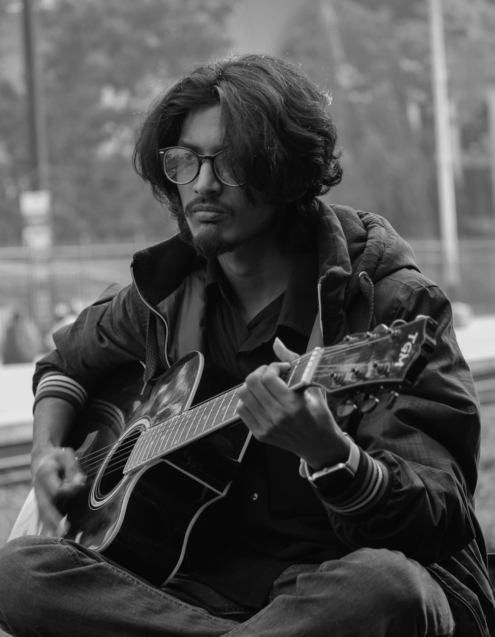 man playing acoustic guitar in grayscale
