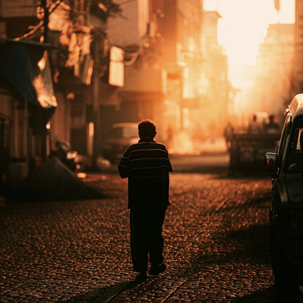 homem em jaqueta preta andando na rua durante o dia