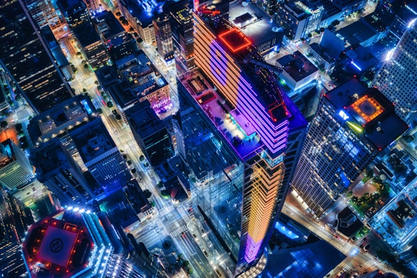 A vibrant aerial view of a neon-lit digital cityscape glowing under a night sky, alive with energy and movement.