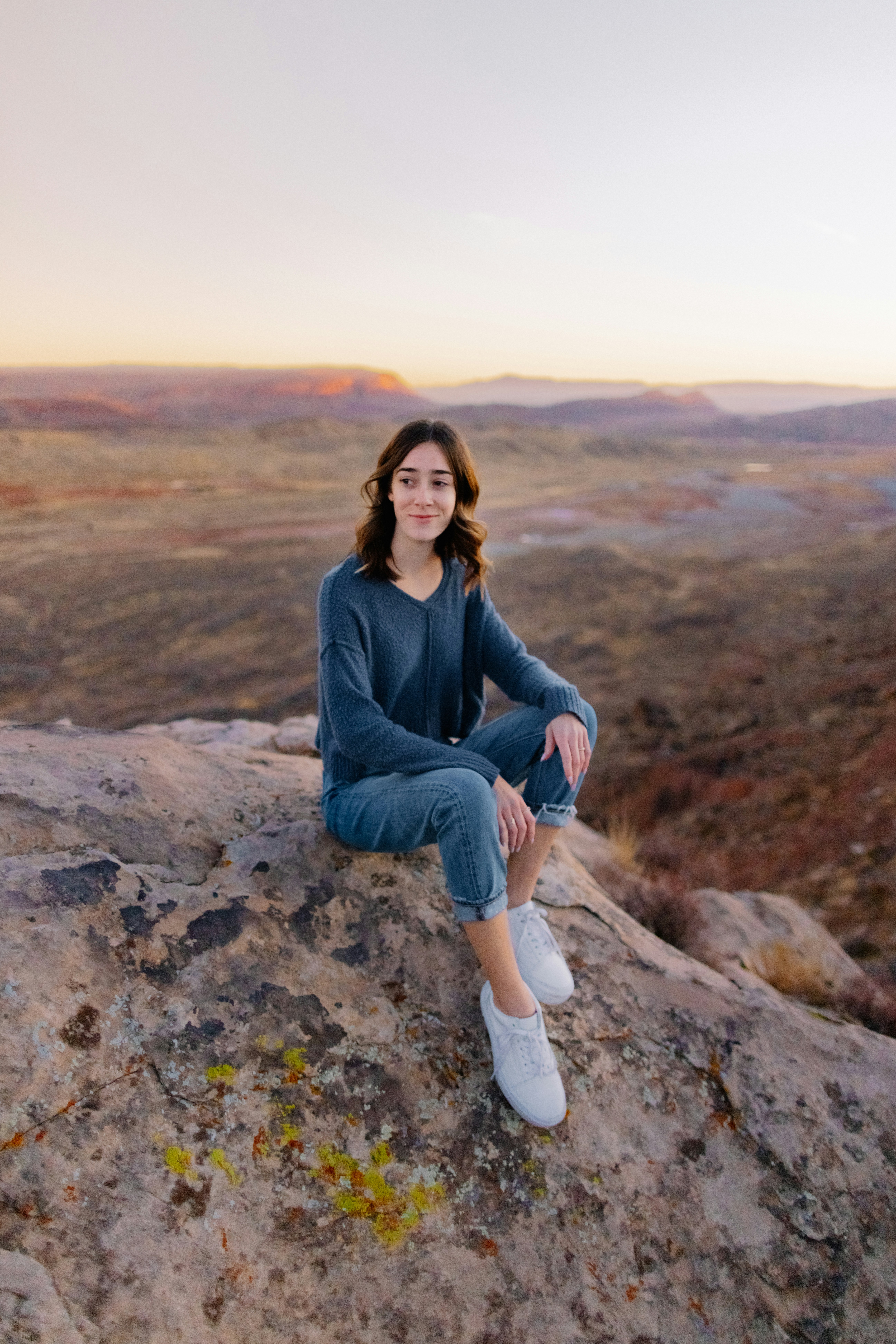 낮에 바위에 앉아 있는 파란색 데님 재킷을 입은 여자