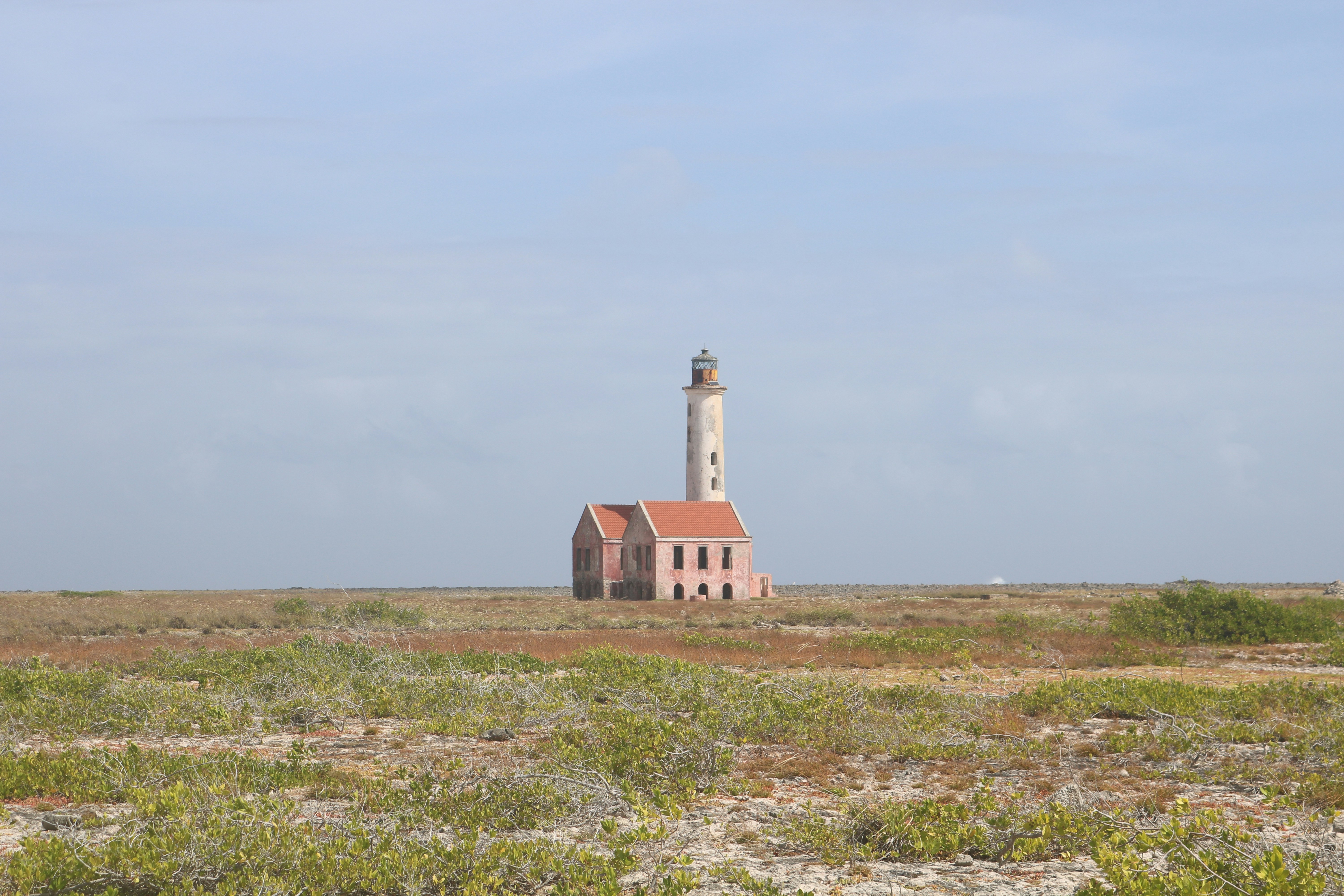 brown and white concrete house on green grass field under white sky during daytime