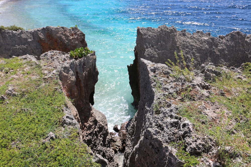 green and brown rocky mountain beside blue sea during daytime