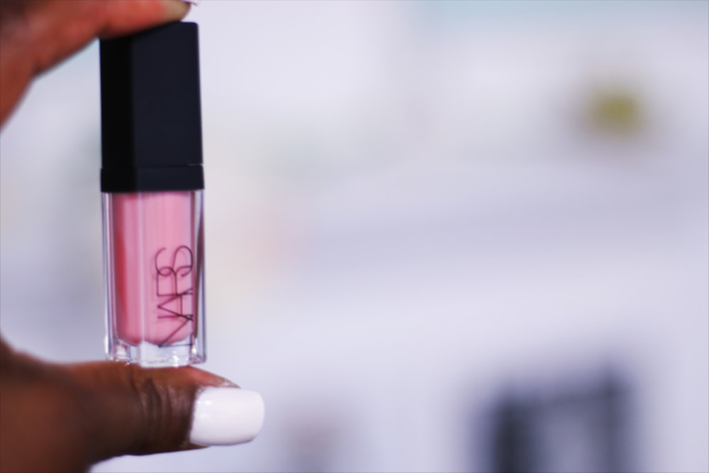 person holding pink lipstick in close up photography