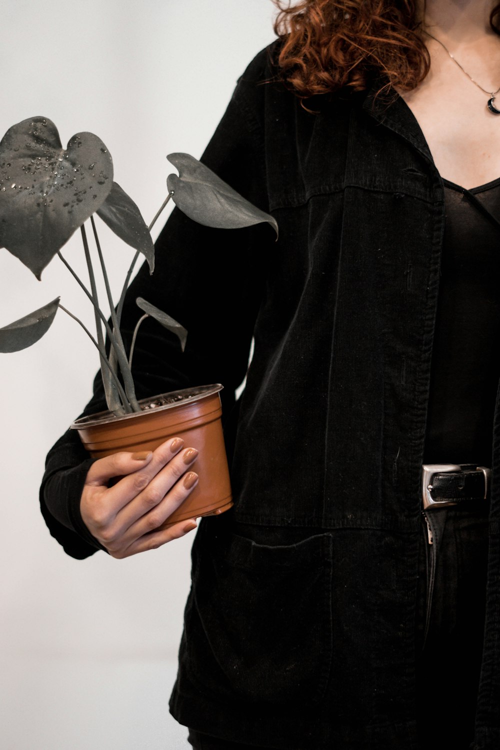 woman in black zip up jacket holding brown ceramic mug