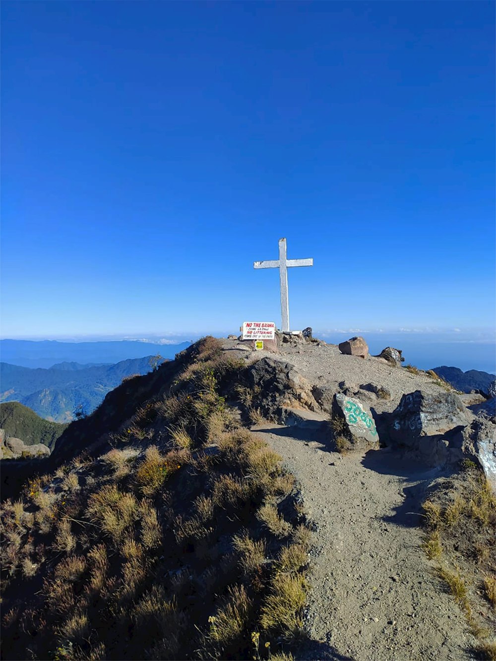 white cross on brown rock under blue sky during daytime