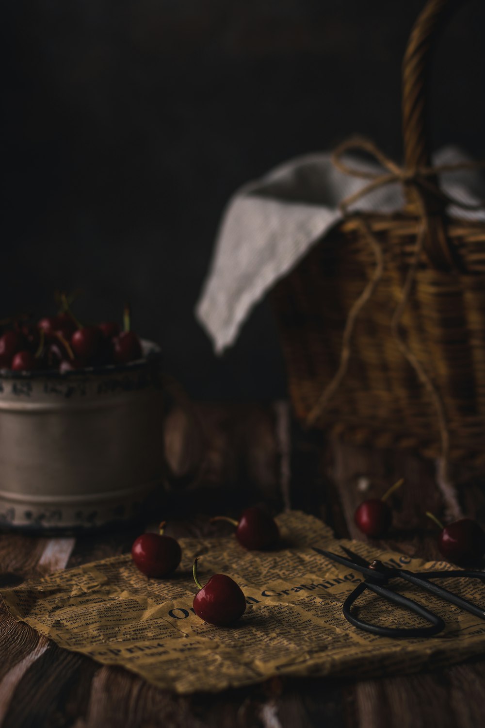 a basket of cherries on a table next to a cake