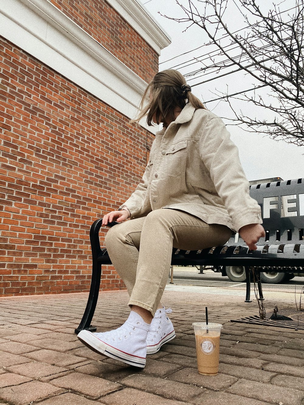 woman in beige coat sitting on black metal bench