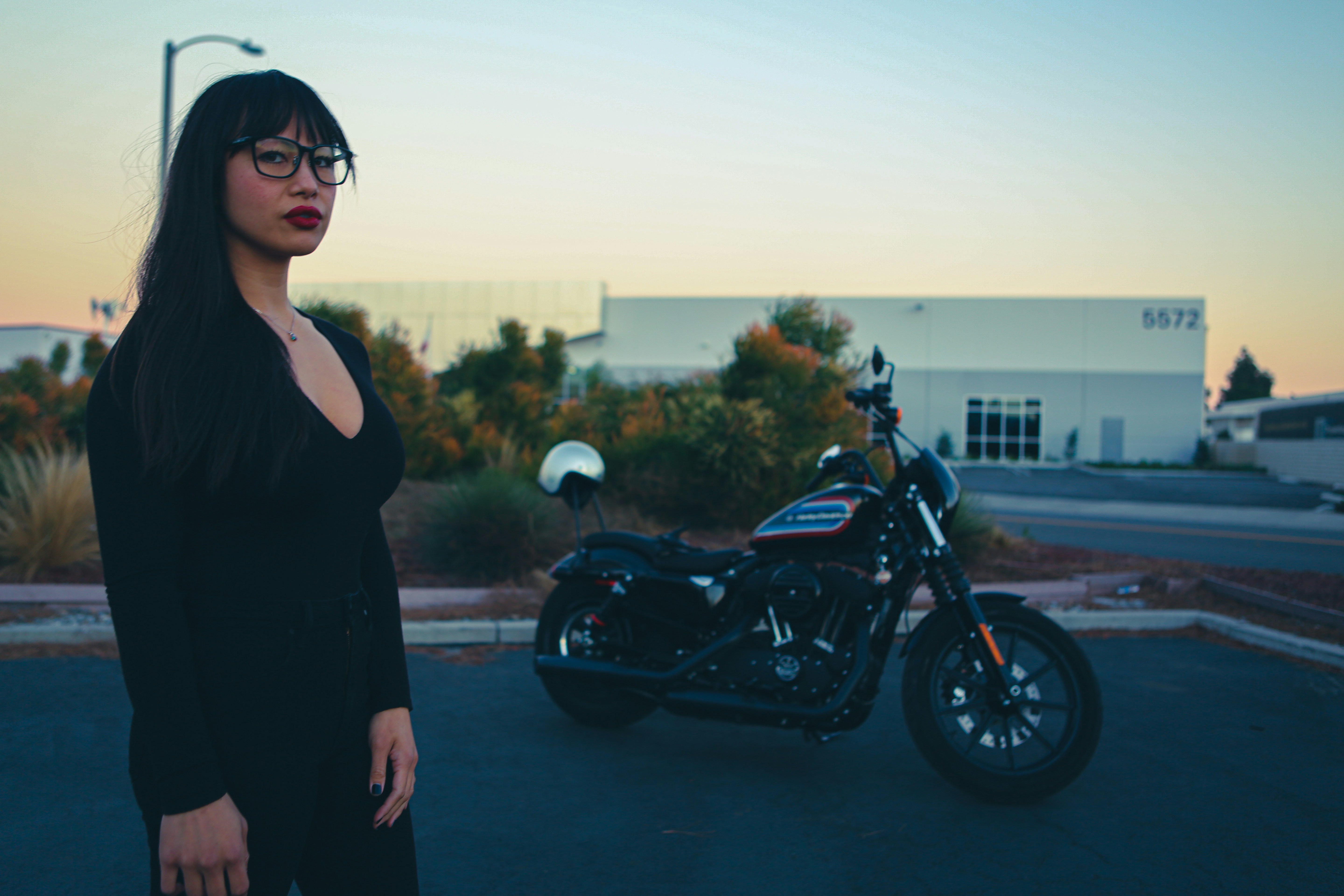 woman in black tank top standing beside black motorcycle during daytime