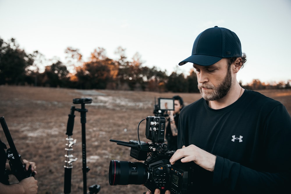 man in blue crew neck t-shirt holding black dslr camera