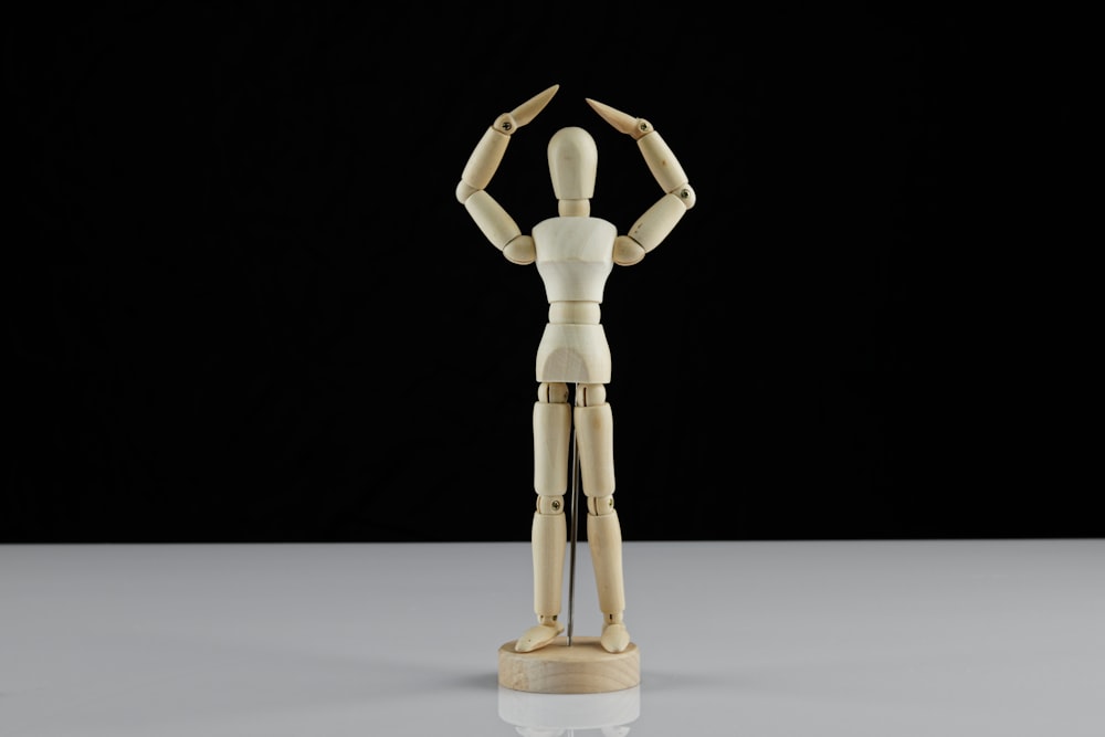 figura humana de madera marrón sobre mesa blanca