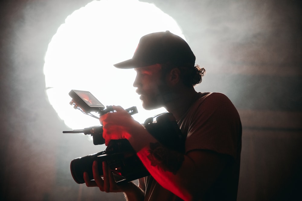 man in red t-shirt and black hat holding a black smartphone