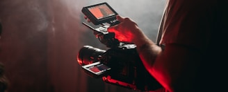 man in white t-shirt holding black video camera