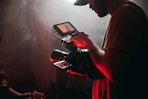 man in white t-shirt holding black video camera