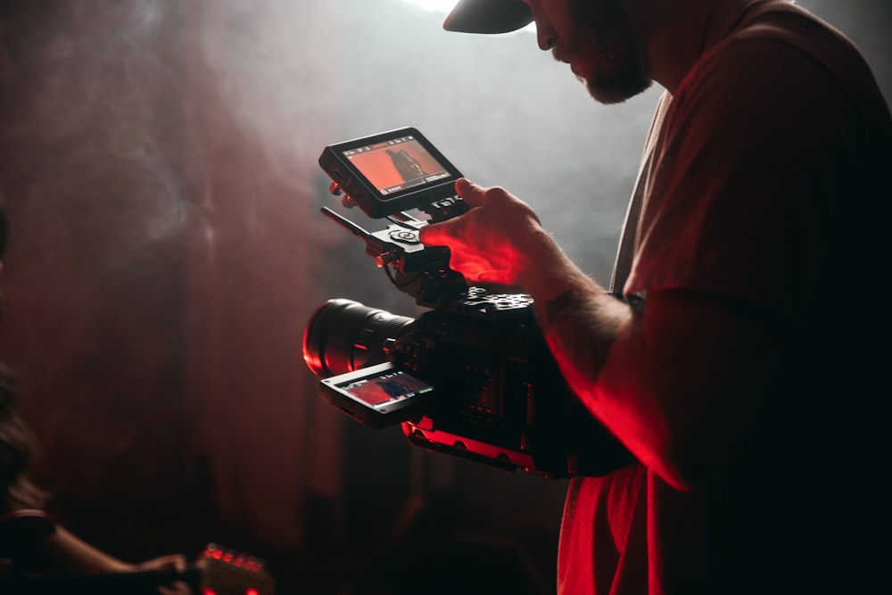 man in white t-shirt holding black video camera