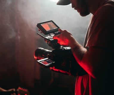 man in white t-shirt holding black video camera