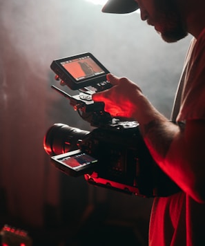 man in white t-shirt holding black video camera