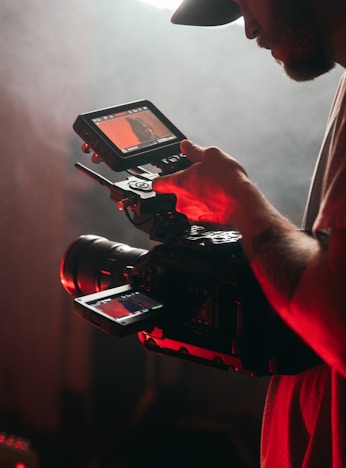 man in white t-shirt holding black video camera