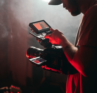 man in white t-shirt holding black video camera