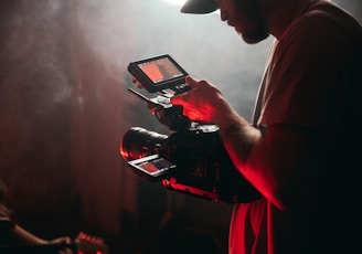 man in white t-shirt holding black video camera