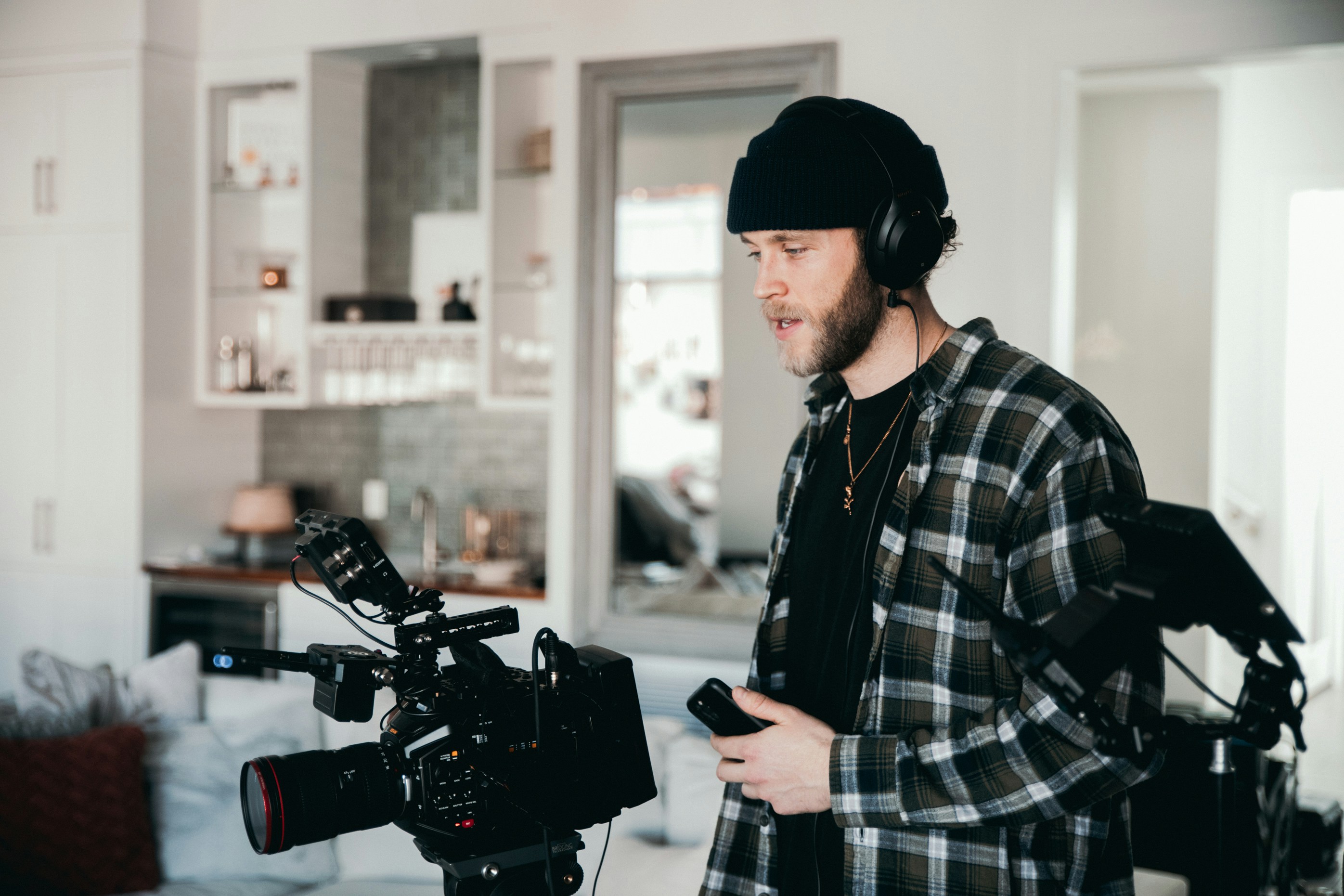 A man stands next to his video camera, filming while generating AI voice for YouTube videos.