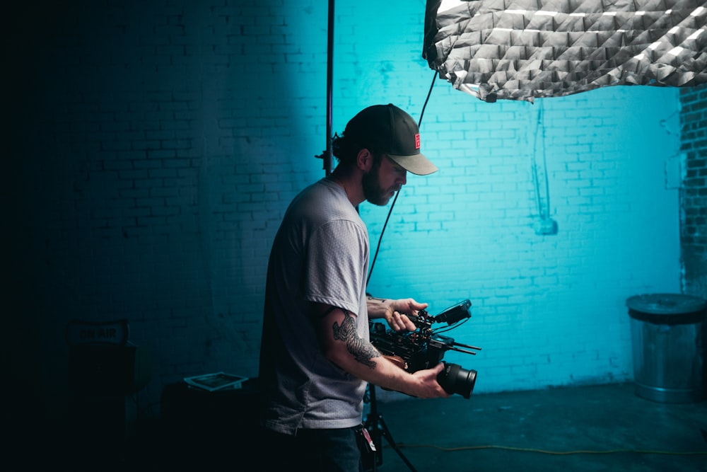 man in white crew neck t-shirt holding black dslr camera