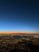 A panoramic view of a vibrant city skyline at dusk with lights beginning to sparkle.