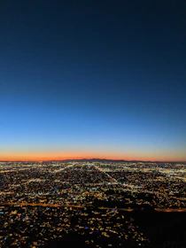 A panoramic view of a vibrant city skyline at dusk, lights twinkling under a soft white sky.