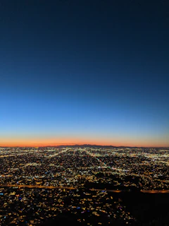 A panoramic view of Qidra’s bustling entertainment district at sunset, with colorful lights and lively crowds.