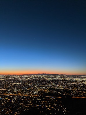 A panoramic cityscape at dusk with glowing electric blue lights reflecting the brand's accent color.