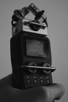 Hands holding a digital voice recorder ready for transcription.