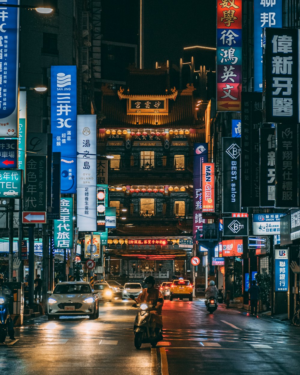 cars on road between high rise buildings during night time