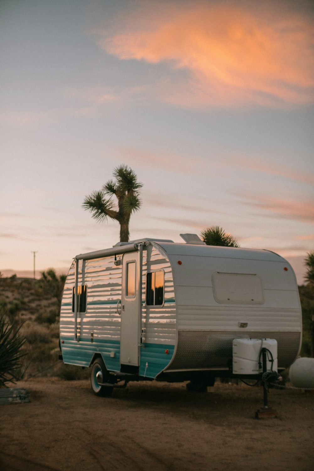 white and blue rv trailer on green grass field under white sky during daytime