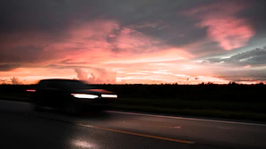 Dynamic shot of a Dodge Charger speeding down a highway at sunset.