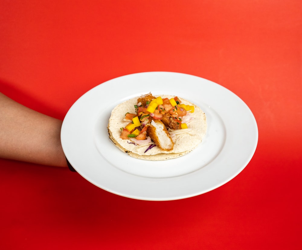 person holding white ceramic plate with food