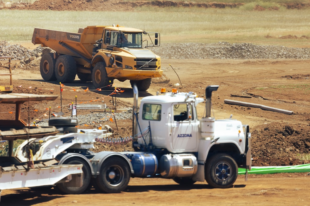 white and yellow truck on brown dirt road during daytime