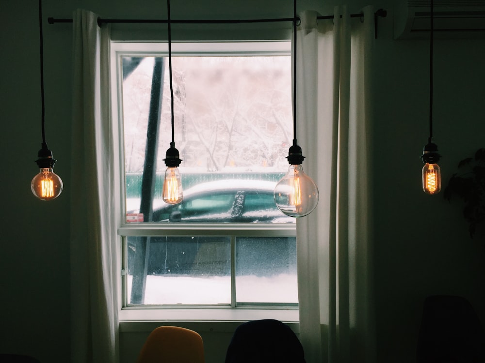 a window with three light bulbs hanging from it
