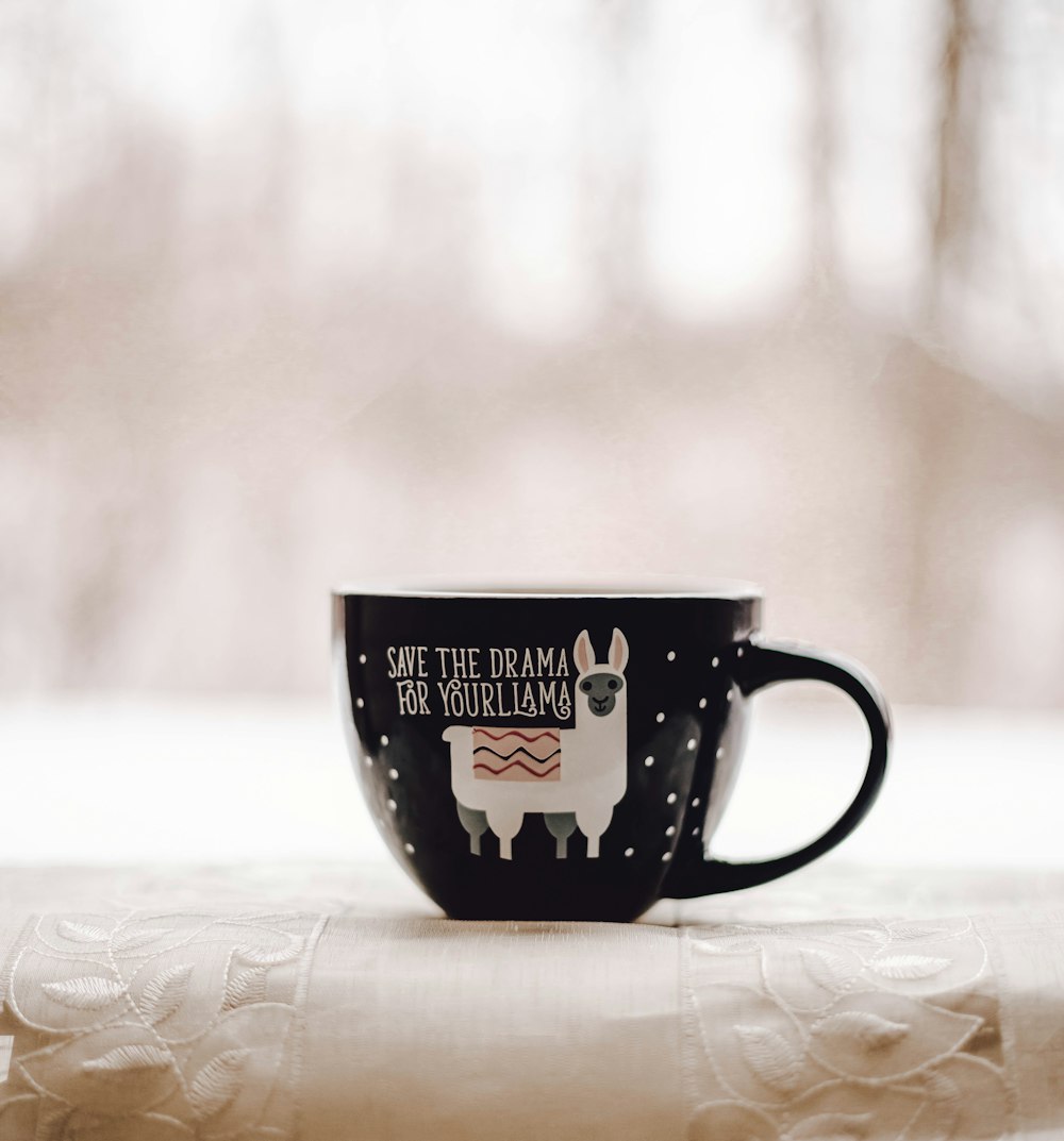 black and white ceramic mug on white and brown floral textile