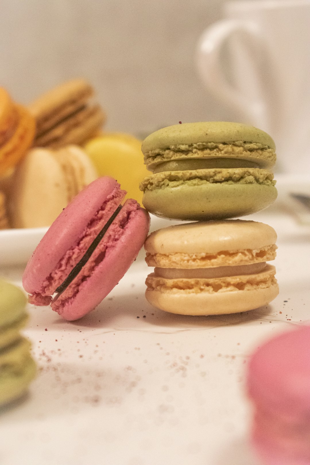 three pink and yellow macaroons on white ceramic plate