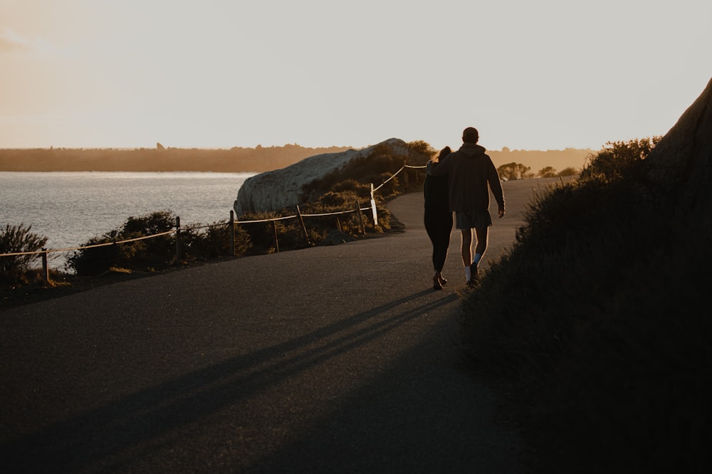 man in black jacket walking on gray asphalt road during daytime