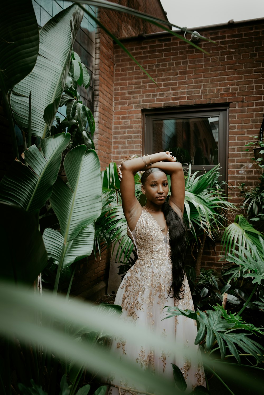 woman in white floral lace dress standing near green plant