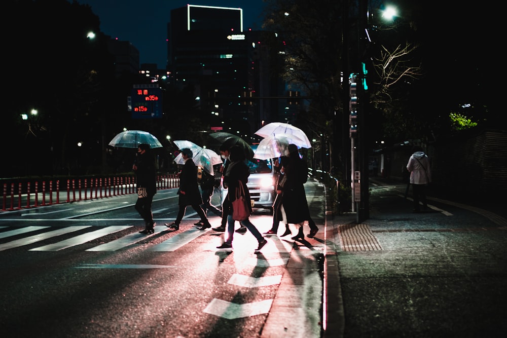 a group of people walking across a street holding umbrellas