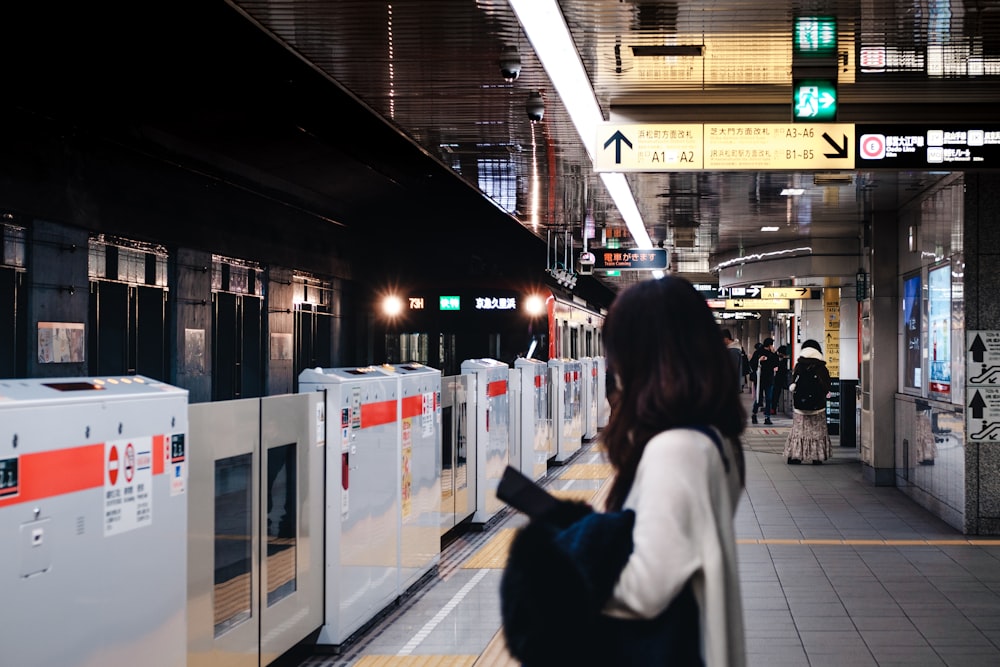 a woman standing next to a train at a train station