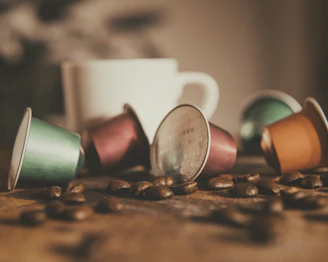 Close-up of biodegradable coffee capsules spilling out of a rustic burlap sack on a wooden table.