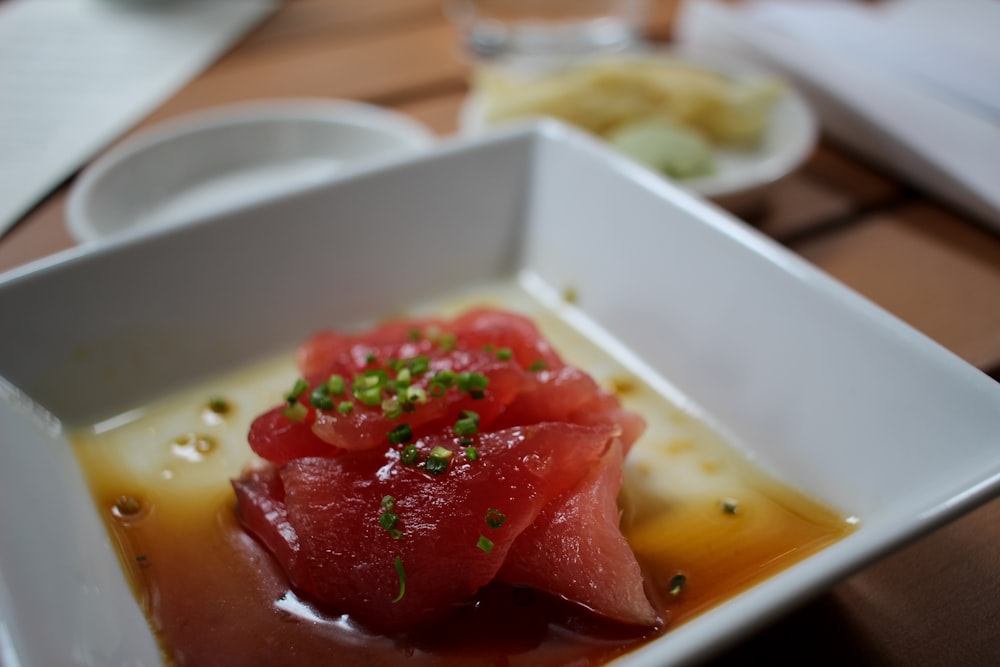 a square white plate topped with food on top of a wooden table